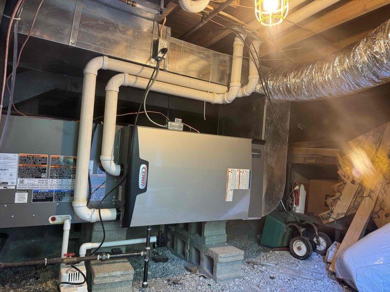 Completed full HVAC system installation including Lennox gas furnace and air conditioning unit with ductwork modifications. Installed air handler unit in basement utility area with proper mounting and leveling, connected white PVC condensate drain lines with appropriate vertical and horizontal runs, and integrated condensate pump for drainage management. Positioned outdoor AC condenser unit on concrete pad with gravel base for proper drainage and vibration isolation. Ran refrigerant line sets between indoor and outdoor equipment with proper insulation and securing. Modified existing ductwork with flexible silver duct connections to air handler, ensuring proper airflow distribution throughout the system. Completed all electrical connections including power supply conduits, control wiring between components, and safety disconnect installation. Installed all required safety labels and manufacturer specifications on equipment. Secured all piping, wiring, and ductwork to structural framing 