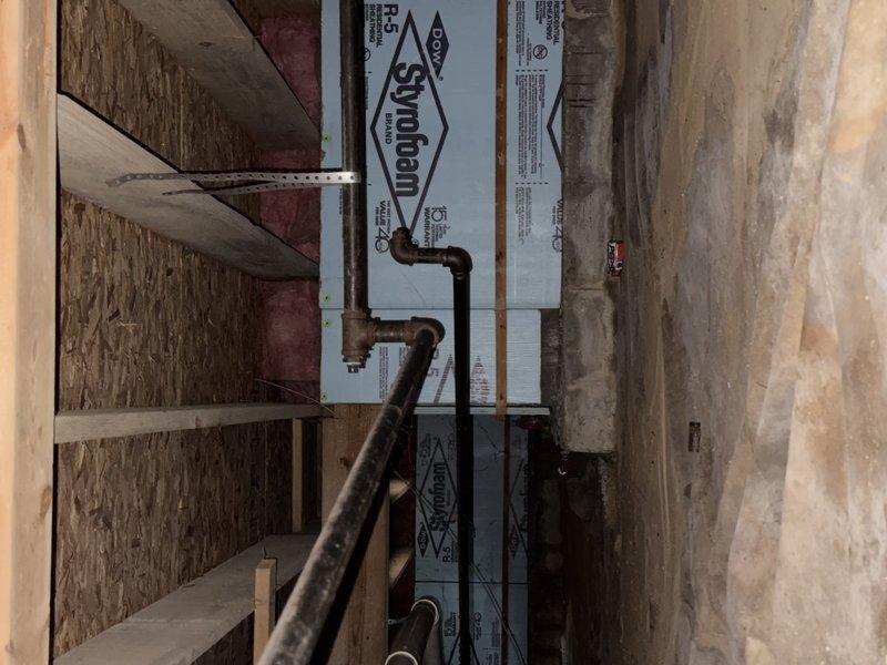Conducted a complimentary estimate for gas line replacement in an unfinished basement utility space. Evaluated existing black iron piping installation running horizontally through wall penetrations with foam insulation sealing, and assessed vertical gas piping routed through wall framing with rigid foam board insulation panels between studs.