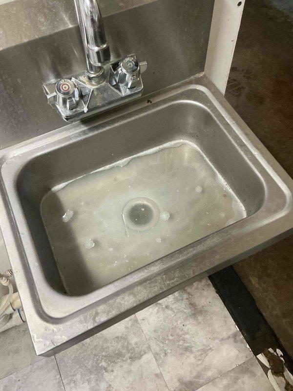 Responded to commercial facility for clogged floor drain beneath utility sink. Successfully cleared obstruction in floor drain using appropriate drain cleaning equipment. Verified proper drainage flow through PVC drain assembly and confirmed all connections were functioning correctly upon completion.