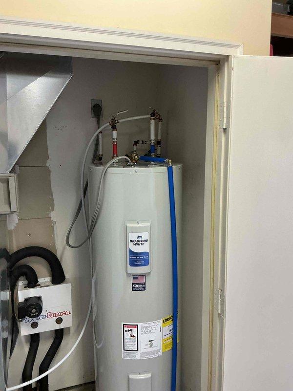 # Plumbing Install - Tanked Water Heater

Replaced existing 50-gallon electric water heater with new unit in residential utility closet. Disconnected electrical supply and plumbing connections from old water heater, then removed unit from service location. Positioned new water heater on elevated base for proper installation height and code compliance. Connected incoming cold water supply line and outgoing hot water distribution line using appropriate copper piping and brass fittings. Installed temperature and pressure relief valve with discharge pipe extension. Secured all plumbing connections and verified proper valve operation, including red-handled shutoff valve for system isolation. Reconnected electrical supply to unit per manufacturer specifications. Tested water heater operation, checked for leaks at all connection points, and verified proper heating function. Installation completed with all safety labels and energy guide information visible and accessible for future reference.