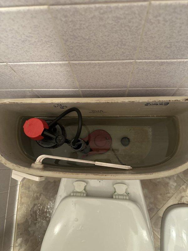 Responded to residential service call for toilet tank repair. Upon inspection, found aging flush valve assembly and fill valve mechanism with visible mineral deposits and hard water buildup throughout tank interior. Removed and replaced complete internal tank components including fill valve assembly, flush valve, flapper, and connecting hardware. Installed new blue-capped fill valve with refill tube and new flush valve system. Adjusted water level to manufacturer specifications and tested flush cycle for proper operation. Verified all connections were secure and leak-free before completing service.