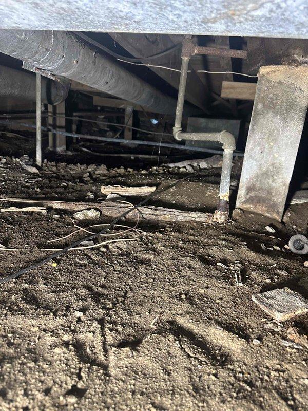 Responded to reported gas leak beneath structure. Conducted thorough inspection of crawl space and located gas piping system running through underfloor area. Performed comprehensive pressure test on all accessible gas lines to identify leak source. Inspected exposed piping, connections, and joints throughout crawl space, noting aged infrastructure and environmental exposure. Also examined HVAC unit and associated gas connections at floor level, identifying compromised piping at base of appliance. Documented all findings with photographic evidence showing pipe routing, support structures, and condition of gas delivery system. Verified leak location and assessed severity to determine appropriate repair methodology. Recommended immediate corrective action to restore system integrity and ensure safe operation.