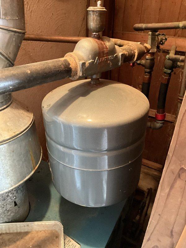 Conducted comprehensive evaluation of aging 40-year-old residential boiler system. Documented existing equipment conditions including expansion tank, associated piping infrastructure, and water heater installation. Photographed significant corrosion on brass fittings, valve assemblies, and copper piping showing oxidation and patina formation, indicating advanced system age and potential reliability concerns for future operation.