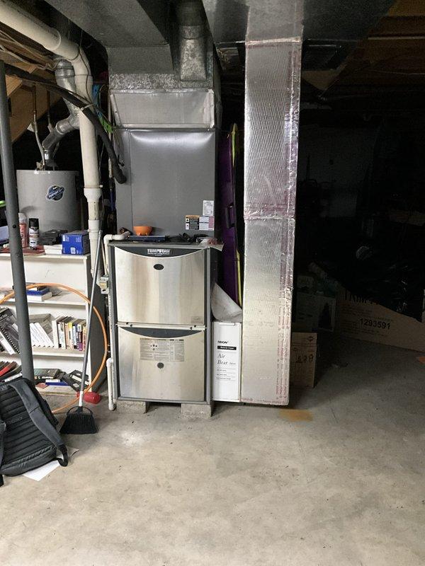 Comfort Consultant conducted a comprehensive Home Comfort Evaluation of the existing HVAC system, including a cylindrical stainless steel furnace unit located in the basement mechanical room and an outdoor air conditioning condenser unit with metal grille enclosure. Assessment included documentation of the current system configuration, ductwork layout, refrigerant line routing, and overall equipment condition to provide the customer with replacement options and recommendations for upgraded home comfort solutions.