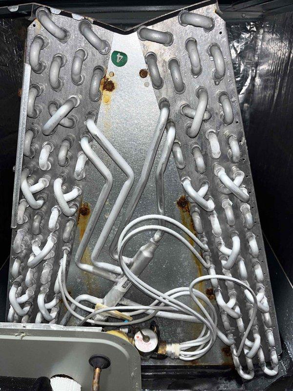 # HVAC Heating Maintenance Completed

Performed comprehensive heating maintenance on HVAC system under Basic Renew plan. During inspection, discovered significant ice buildup on evaporator coil assembly, indicating restricted airflow or potential refrigerant issues. Documented condition of coil with heavy frost accumulation on lower fins and condensation throughout unit. Installed new 20x20x4 filter as part of maintenance agreement coverage through 2030. Inspected interior components including copper tubing, aluminum fins, and electrical connections. Noted rust-colored staining on metal surfaces and dust accumulation on upper coil sections. System requires monitoring for proper defrost cycle operation and airflow restoration.