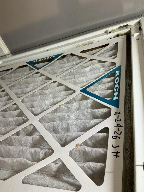 Completed monthly CCHP cooling maintenance visit under membership plan. Replaced 16x20x1 air filter with Koch brand filter, noting moderate dust accumulation on removed filter dated 12-25. Measured supply air temperature at 71.02°F using infrared thermometer. Observed water damage and potential mold growth on filter housing and surrounding door frame area, with visible staining and discoloration on white trim and gray wall surfaces indicating ongoing moisture intrusion issue that may require further investigation.