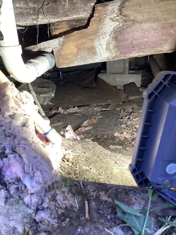 Responded to customer complaint regarding inadequate heating performance during previous winter season despite thermostat set to 90°F. Performed crawlspace inspection to assess ductwork condition and identify heat loss issues. Accessed difficult crawlspace area with limited clearance and navigated through debris and challenging conditions. Documented extensive deterioration of crawlspace insulation, including damaged and detached foil-backed vapor barrier material on foundation walls. Observed exposed floor joists with moisture staining and discoloration indicating potential air infiltration pathways. Identified compromised building envelope allowing conditioned air loss and reducing system efficiency. Placed ventilation fan in crawlspace for air circulation and moisture management. Photographed existing conditions including deteriorated insulation, damaged vapor barrier, exposed soil floor, and aged exterior gas meter installation with corroded piping. Recommended comprehensive ductwo