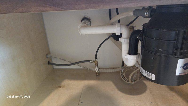 Responded to water leak under kitchen sink. Upon arrival, found disconnected drain pipe beneath sink causing active water leak. Inspected under-sink plumbing assembly including garbage disposal unit, P-trap, and drainage connections. Reconnected and secured loose drain pipe, verified all PVC connections were properly sealed and tightened. Tested system by running water through sink and disposal to confirm leak was resolved and all connections remained secure under flow. Also inspected toilet tank mechanism during visit and documented condition of flush valve assembly. System restored to proper working order with no active leaks detected upon completion.