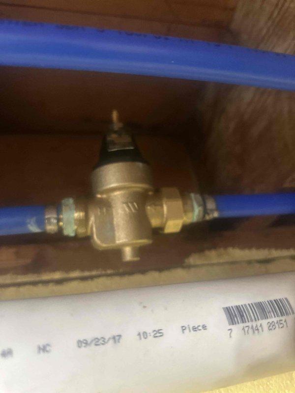 Returned to property to replace the pressure reducing valve on the main water supply line. Removed the existing PRV and installed a new brass pressure reducing valve with compression fittings on the blue PEX piping system. The valve was properly positioned and secured within the wooden framing cavity, with the adjustment mechanism accessible for future pressure adjustments. System was tested and confirmed to be operating within proper pressure parameters.