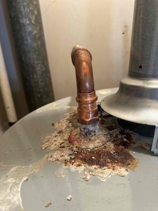 Completed water heater maintenance flush on 9-year-old residential tank system. Addressed significant corrosion buildup on hot water outlet copper fitting, which showed extensive white, tan, and reddish-brown deposits indicating active leak and long-term water damage. Performed tank flush procedure to remove sediment accumulation and inspected all connections for integrity. The hot water outlet exhibited severe deterioration at the base connection point with visible moisture damage and oxidation on surrounding components. Documented existing corrosion conditions on copper piping and connection points for future monitoring. System operational upon completion, though outlet fitting corrosion will require continued observation or potential replacement to prevent further deterioration.