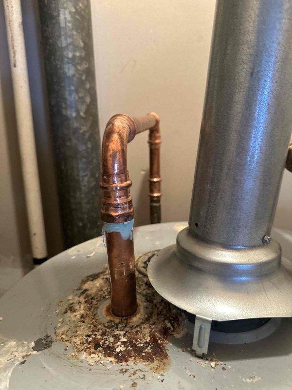 Completed water heater maintenance flush on 9-year-old residential tank system. Addressed significant corrosion buildup on hot water outlet copper fitting, which showed extensive white, tan, and reddish-brown deposits indicating active leak and long-term water damage. Performed tank flush procedure to remove sediment accumulation and inspected all connections for integrity. The hot water outlet exhibited severe deterioration at the base connection point with visible moisture damage and oxidation on surrounding components. Documented existing corrosion conditions on copper piping and connection points for future monitoring. System operational upon completion, though outlet fitting corrosion will require continued observation or potential replacement to prevent further deterioration.