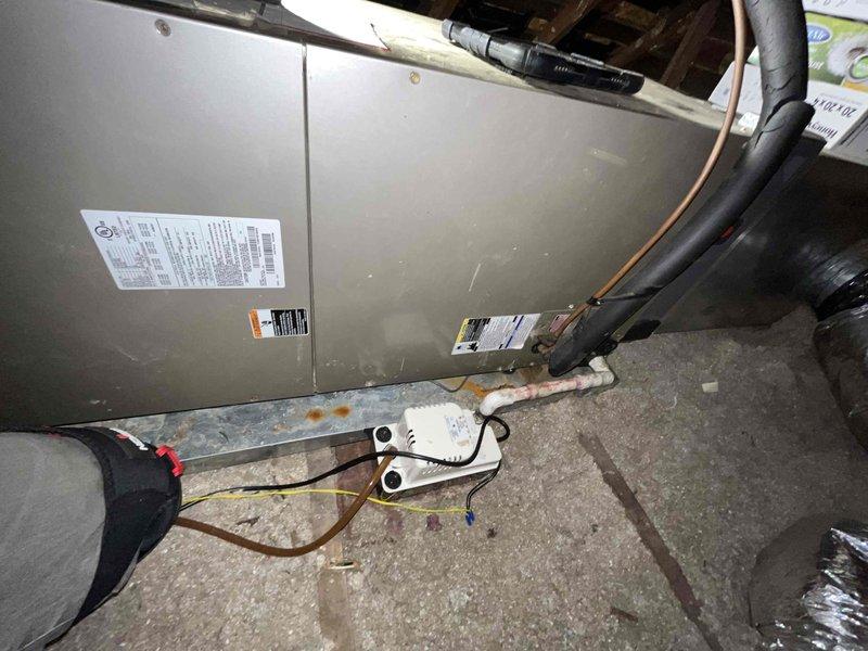 Performed a heating maintenance inspection on the attic-mounted air handler, checking the blower assembly, condensate pump, drain connection, and refrigerant line insulation. Observed dust and debris buildup on the blower wheel blades and minor surface rust at the base of the unit near the drip pan, and noted both for follow-up cleaning and monitoring.