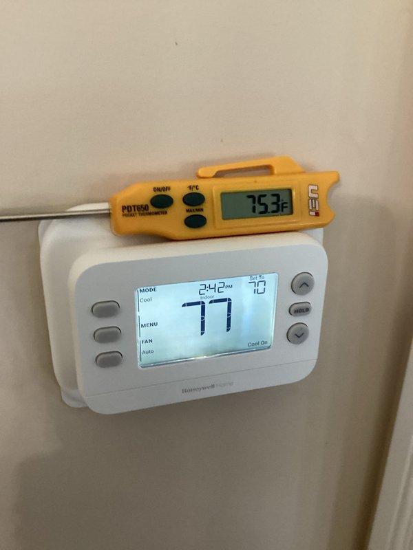 Responded to a thermostat complaint on a Lennox EL16XC1 air conditioning system. Inspected the wall-mounted thermostat, which was a Honeywell Home unit rather than the reported Lennox iComfort, and found it operating in Cool mode with a 70°F set point and "Cool On" displayed. Verified current space temperature with a calibrated pocket thermometer (75.3°F against a 77°F thermostat reading), noting the unit was actively calling for cooling with no visible damage or abnormal conditions at the thermostat location.