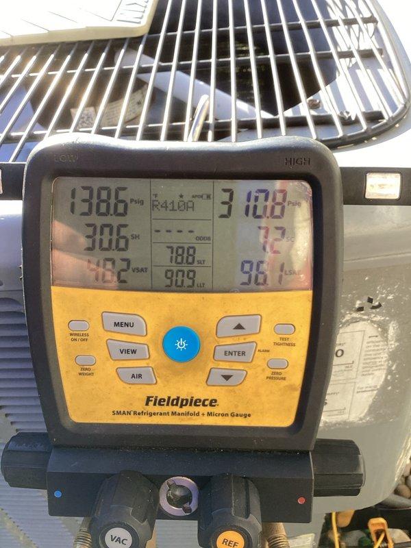Performed diagnostic evaluation of the Daikin R410A split-system condenser in response to a suspected low refrigerant charge. Connected digital manifold gauges and recorded operating readings of 138.6 psig suction and 310.8 psig discharge, with 30.6°F superheat and 7.2°F subcooling. The condenser exterior showed no visible frost, ice, or leak indicators. Readings are consistent with a system operating below optimal charge, and further leak detection and charge correction are recommended.