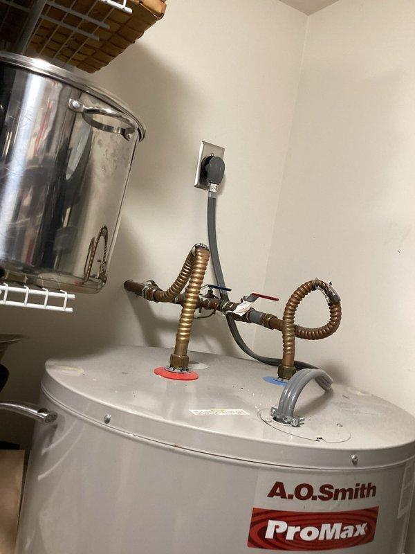 Performed an on-site assessment of the existing A.O. Smith ProMax electric water heater, documenting the tank, corrugated flexible water connectors, inlet/outlet shutoff valve assembly, and cord-and-plug electrical connection for replacement estimating. Fittings showed minor age-related tarnish with no visible leaks, rust, or damage. Also documented the garage panel and deep freeze area to evaluate routing for a dedicated circuit.