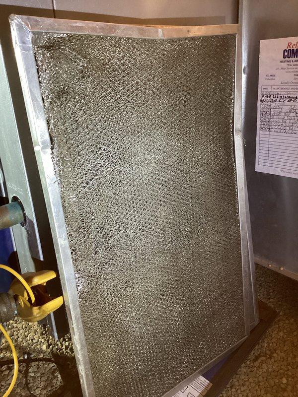 Performed annual heating system maintenance, inspecting the supply ductwork, damper assembly, linkage hardware, and control components for proper operation and airflow. Removed and inspected the metal mesh air filter, which showed heavy dust and debris loading, and documented the condition for filter cleaning or replacement to restore proper airflow. Verified all components were free of frost, ice, and corrosion, and completed the maintenance log entries.