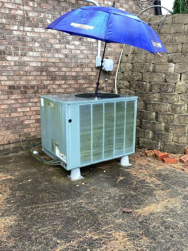 Performed seasonal tune-up on a 2013 model outdoor condensing unit, documenting unit data and condition. Inspection revealed heavy dust, lint, and debris matting on the condenser coil surface, along with leaves and debris on the cabinet floor, restricting airflow; coil and cabinet were cleaned to restore heat transfer. Noted weathered cabinet finish and an umbrella placed over the fan opening, which should be removed to prevent airflow obstruction and fan damage, and checked the electrical disconnect, wiring, and refrigerant line insulation.