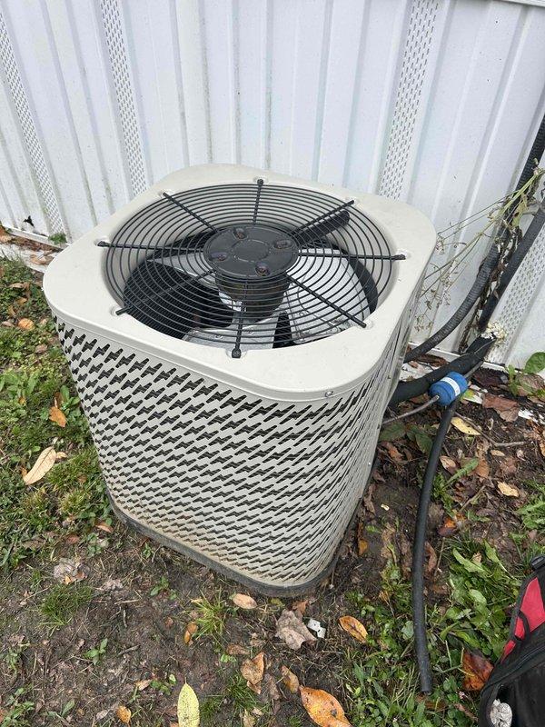 Responded to a no-cool complaint on a 5-year-old residential split-system condenser. Inspected the outdoor unit and found the compressor with surface rust and corrosion on the lower end cap, dirt and debris buildup on the housing, and leaf litter around the base. Verified the condenser fan and motor, evaluated the compressor and associated electrical connections and sensor wiring, and checked the refrigerant line set, noting tarnished copper tubing; findings indicate a possible compressor or refrigerant circuit issue contributing to the loss of cooling.