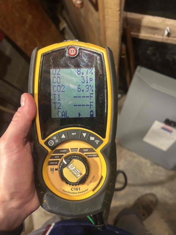 Evaluated the gas-fired boiler system, including an inspection of the heat exchanger, venting, control module, circulator pump, and associated piping with the front cover removed. Performed a combustion analysis using a handheld analyzer, recording O2 at 8.7%, CO at 31 ppm, and CO2 at 6.9%, to assess burner operation and combustion efficiency. Noted general age-related wear, dust accumulation, and light surface corrosion on the cabinet.