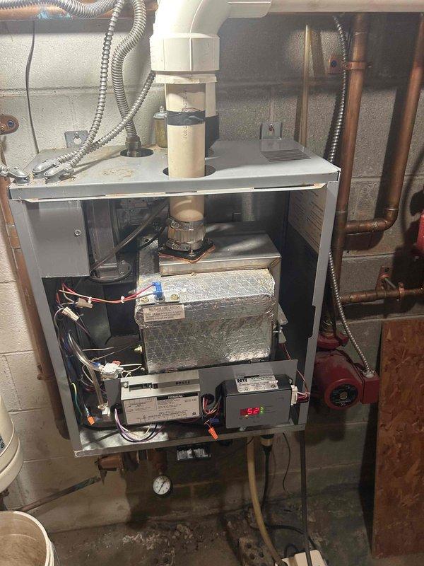 Evaluated the gas-fired boiler system, including an inspection of the heat exchanger, venting, control module, circulator pump, and associated piping with the front cover removed. Performed a combustion analysis using a handheld analyzer, recording O2 at 8.7%, CO at 31 ppm, and CO2 at 6.9%, to assess burner operation and combustion efficiency. Noted general age-related wear, dust accumulation, and light surface corrosion on the cabinet.