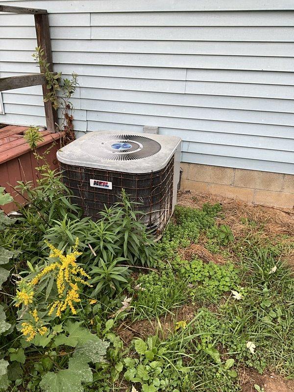 Evaluated a 1,500 sq ft residence with original 30+ year-old natural gas furnace and split AC system, with reusable crawlspace ductwork supporting a direct changeout. Documented failing fan and compressor controls and corrosion on the condenser coil fins, with heavy vegetation encroaching on the outdoor unit and the electrical panel inspected for equipment circuiting. Prepared two replacement options, an 80% gas furnace only and a furnace paired with a 15.2 SEER2 AC for utility rebate eligibility, with a new thermostat and C-wire installation itemized separately and the estimate validity period provided in writing.