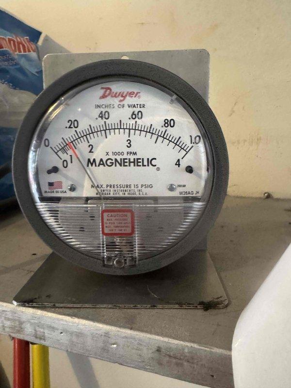 Completed a full Lennox heat pump system installation, including setting the outdoor condenser unit on a level pad and routing insulated refrigerant lines and electrical conduit along the foundation wall with secured clips. Installed a Dwyer Magnehelic differential pressure gauge on the indoor air handling equipment to monitor static pressure and verify airflow performance, with the reading within the normal low-range operating scale at startup.