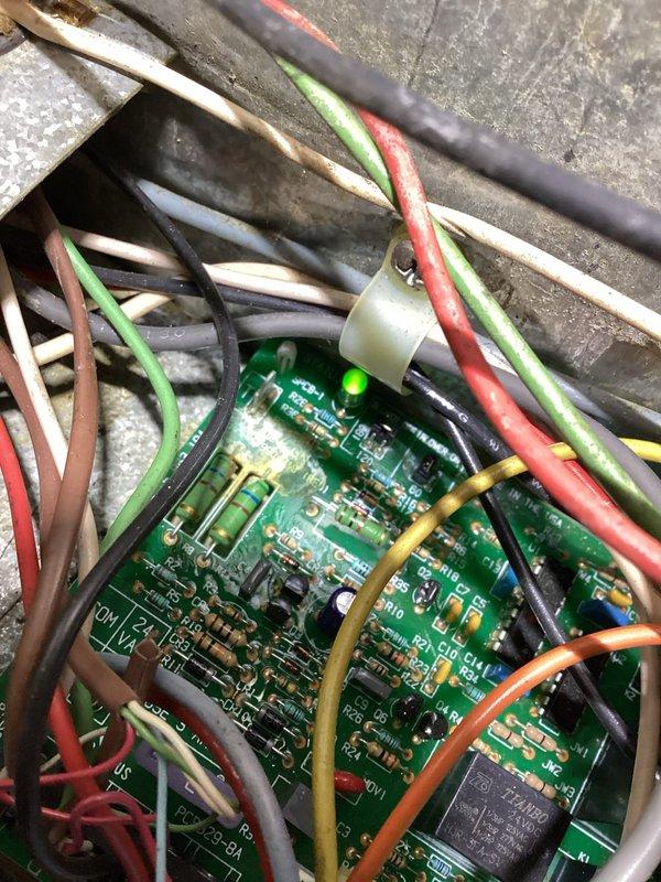 Responded to a no-heat call with no system response at the thermostat. Inspected the Honeywell analog thermostat and the furnace control board, verified 24 VAC control voltage and board operation (status LED illuminated), and noted discoloration on the board near the resistors indicating possible heat stress or contamination. Evaluated the control circuit and relay to determine the cause of the heat call failure.