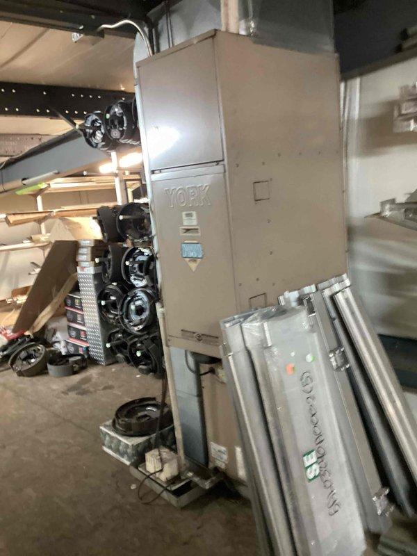 Performed seasonal heating maintenance on a York upright air handler/furnace, inspecting the unit's cabinet, controls, wiring, and surrounding area for signs of damage, rust, or frost, with none observed. Filter size could not be determined and requires documentation. Noted that the unit's clearances are restricted by stored materials, including metal panels leaning against the cabinet, which should be relocated to maintain proper airflow and safe service access.