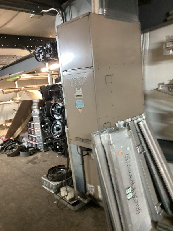 Performed seasonal heating maintenance on a York upright air handler/furnace, inspecting the unit's cabinet, controls, wiring, and surrounding area for signs of damage, rust, or frost, with none observed. Filter size could not be determined and requires documentation. Noted that the unit's clearances are restricted by stored materials, including metal panels leaning against the cabinet, which should be relocated to maintain proper airflow and safe service access.