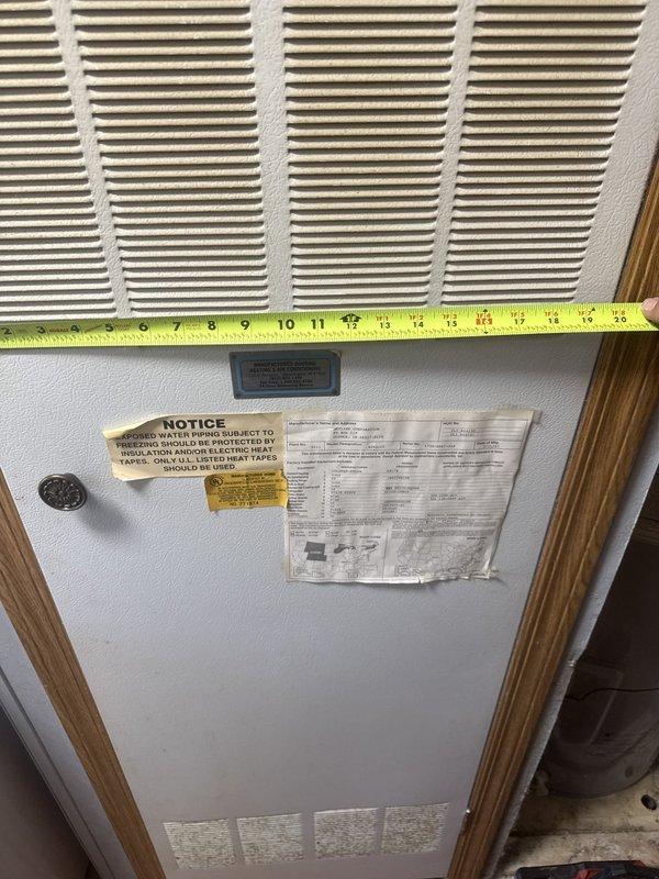 Performed a diagnostic assessment of the electric tank water heater, including electrical testing of the heating element and thermostat circuit with a clamp meter at the exposed access panel. Inspected the adjacent supply piping and valves, noting staining on the pipe near the upper fittings. Measured the furnace room door opening to confirm clearance for replacement equipment.