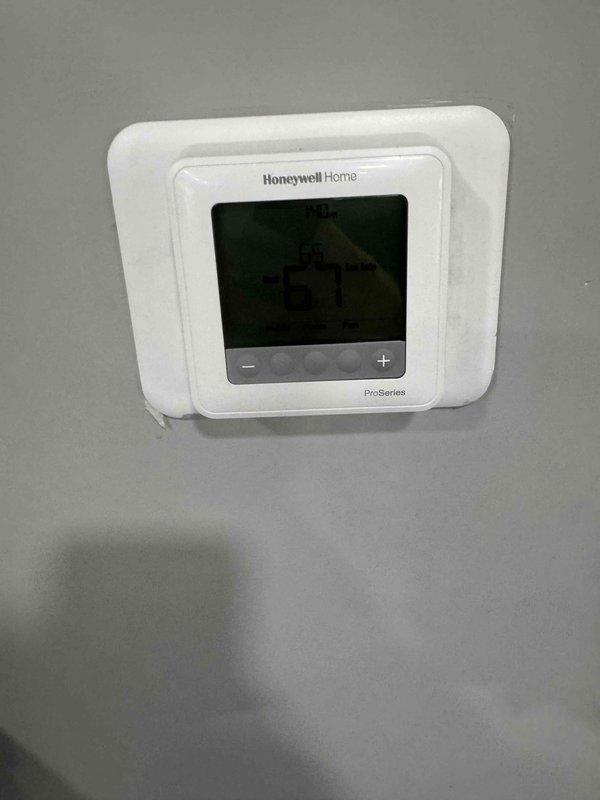Completed installation of a Lennox heat pump system, including the indoor air handler with insulated flex duct and foil-wrapped supply plenum connections, secured with zip ties, and PVC condensate drain routing with elbow fittings. Installed and configured a Honeywell Home ProSeries digital thermostat, which is operating properly and displaying a 67°F reading. Verified the system showed no signs of frost, rust, or visible damage at completion.