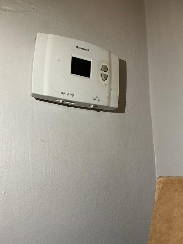 Performed a seasonal HVAC tune-up, inspecting system operation and verifying thermostat function. Confirmed the Honeywell digital thermostat powers on, displays the current temperature reading, and responds to the system selector (Heat/Off/Cool) and fan selector (Auto/On) settings. Noted cosmetic wear and staining on the thermostat housing, with no operational deficiencies identified.