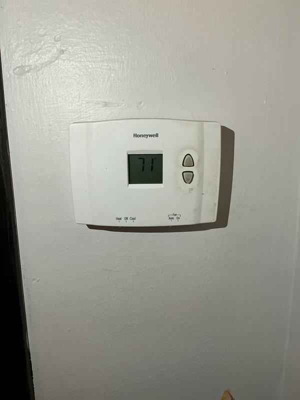 Performed a seasonal HVAC tune-up, inspecting system operation and verifying thermostat function. Confirmed the Honeywell digital thermostat powers on, displays the current temperature reading, and responds to the system selector (Heat/Off/Cool) and fan selector (Auto/On) settings. Noted cosmetic wear and staining on the thermostat housing, with no operational deficiencies identified.