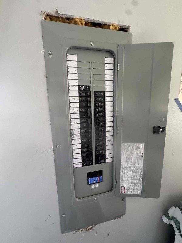 Completed a 200 amp service panel upgrade, installing a new flush-mounted distribution panel with a main breaker and a digital monitoring module, and landing all branch circuits on properly sized breakers. Circuits were identified with handwritten directory labels and the panel schedule was posted inside the door. Wall cutouts were opened to set the enclosure, with surrounding drywall and insulation left exposed for patch and finish work.