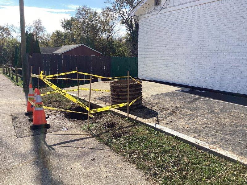 Responded to a leaking commercial main sewer line and excavated the affected section adjacent to the building, establishing a cordoned safety perimeter with caution tape and traffic cones. Exposed the line and identified active leakage, evidenced by standing foamy water and mineral deposits beneath the concrete slab and stacked corrugated pipe sections. The main line was repaired to stop the leak.