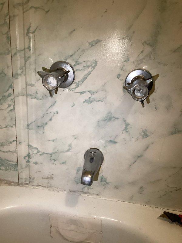 Diagnosed leaking fixtures at the kitchen sink, bathroom sink, and tub, and found heavy mineral scale and corrosion buildup in the tub faucet handle assembly, with worn, tarnished trim and a tape-repaired area on the tub surface. Evaluated the failed garbage disposal for replacement and assessed the installation requirements for the customer's newly ordered dishwasher.