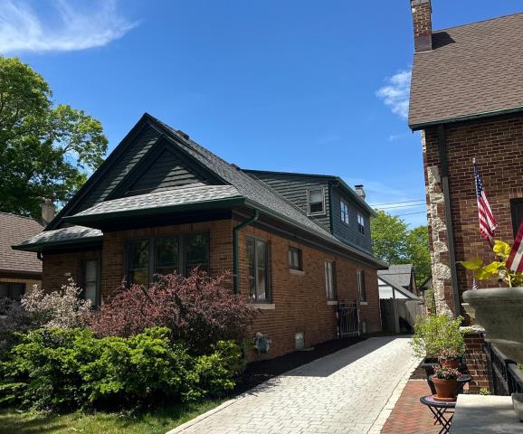 We recently had the opportunity to complete a total exterior update for a home and detached garage in Whitefish Bay! To begin, we cleanly stripped away the old roof layer down to the original boards. For a foundation built to last and fully meet manufacturer warranty standards, we re-decked the entire surface with durable OSB sheathing.   

The highlight of this project is a premium CertainTeed Northgate ClimateFlex impact-resistant shingle system in Granite Gray, fully reinforced with high-performance winter ice and water shield membranes around all the eaves, valleys, and roof penetrations. To match the new look, we custom-fabricated brown steel chimney flashings and neatly tucked new slant-back ventilation units out of sight on the rear facets of the home. Finally, we upgraded the property's water management by installing brand-new 6" seamless aluminum gutters and downspouts in an Evergreen finish to both sides of the garage and the southwest dormer. It was a pleasure helping anot