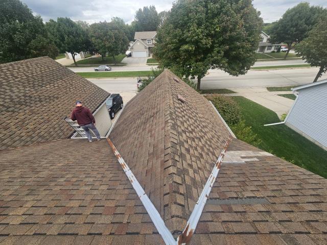 This project in Waukesha centered around specialized metal fabrication and a ventilation transformation for both the home and attached garage! Along with installing a high-performance CertainTeed NorthGate ClimateFlex Class 4 impact-rated shingle system in Heather Blend, we focused on solving unique roofline challenges. Our crew removed the existing power vent, added 12 new brown slant-back roof vents to optimize ventilation, and carefully worked around the existing B-vent and three plumbing stacks with lifetime silicone boots. The highlight of the restoration was the custom chimney work: we detached the surrounding siding to run a six-foot ice and water shield barrier, built a custom 26-gauge coated steel cricket, carefully reinstalled the original siding, and fitted the chimney with a brand-new 24-gauge steel cap. To finish it off, we protected the roof deck with painted "W" style galvanized valley metal and preserved the home's existing gutter system for a seamless, heavy-duty upgra