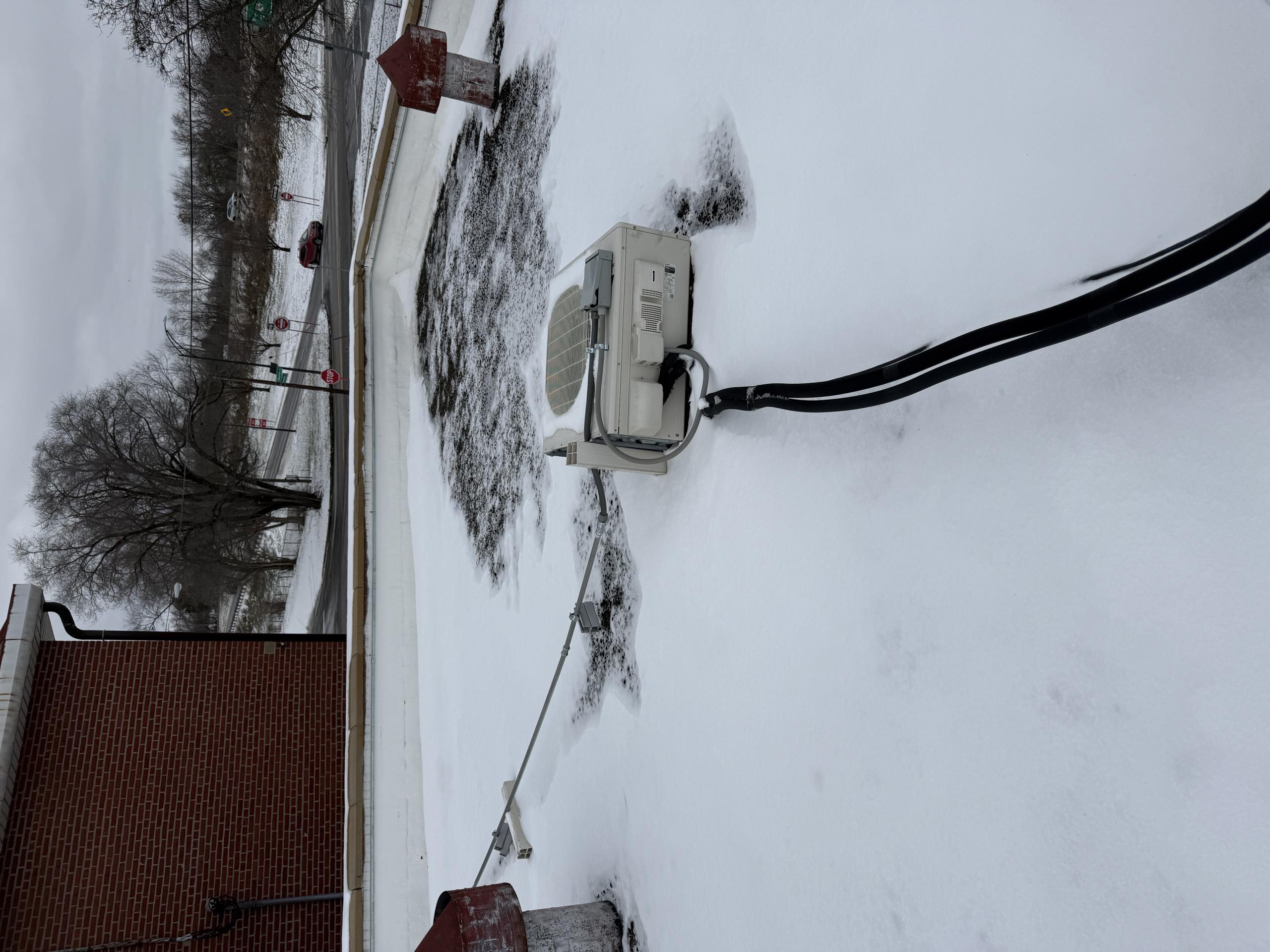 Mini split outdoor unit laying on its back.
I could have blown over from wind or it could have been vandalized. 
Ice on the edge of the roof line makes getting up impossible today
We will need to return after it thaws and assess the damage to the unit
Best case it just needs stood up, allow the Compressor oil to settle back to the bottom for 24hrs and see if it runs
Worst case, the Compressor has failed as a result of laying on its back  and trying to run.  **this will require unit replacement**