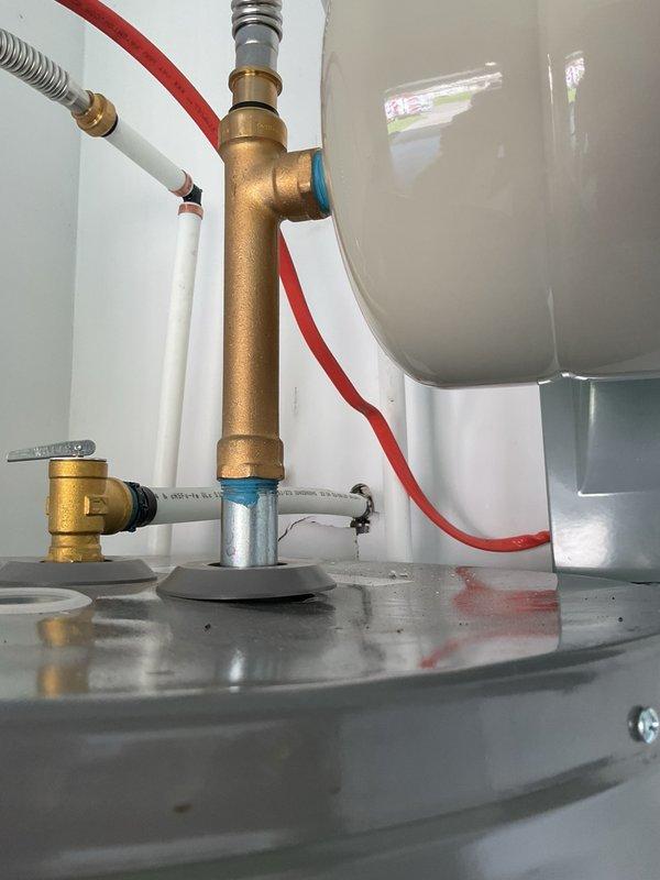Completed installation of HVAC equipment and water heater system in mechanical space. Installed refrigerant line set with proper mounting brackets and secured all connections to manufacturer specifications. Configured water heater plumbing connections including hot and cold water supply lines, installed brass T-fitting assembly with flexible hoses, and verified all connections for proper operation and leak-free performance.