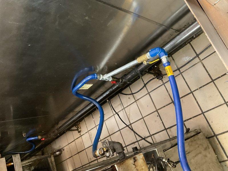 Performed inspection and documentation of gas water heater installation and associated plumbing connections in utility area. Verified proper installation of gas valve assembly, brass fittings, and blue flexible gas supply lines with appropriate safety labeling. Confirmed secure mounting of equipment, proper routing of black electrical conduit, and adequate clearances around unit. Documented condition of tile flooring in mechanical space and existing plumbing infrastructure for service records.