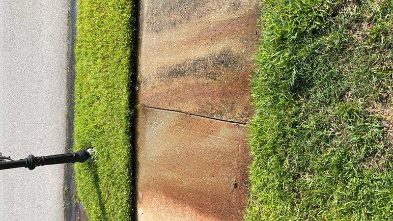 Performed photographic documentation of underground utility access infrastructure. Inspection revealed an open utility access box with standing water and submerged brass valve assembly requiring attention. Additionally documented exterior walkway surfaces including concrete pavers, artificial turf border, and natural grass areas with pressure washing equipment visible in frame for maintenance assessment purposes.