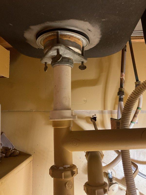 Inspected residential kitchen plumbing and water heater system. Documented under-sink cabinet area and water heater dip tube assembly, including inlet/outlet connections and mounting hardware. All components photographed for service records, with particular attention to water heater tank interior fittings, flexible supply lines, and mounting flange condition.
