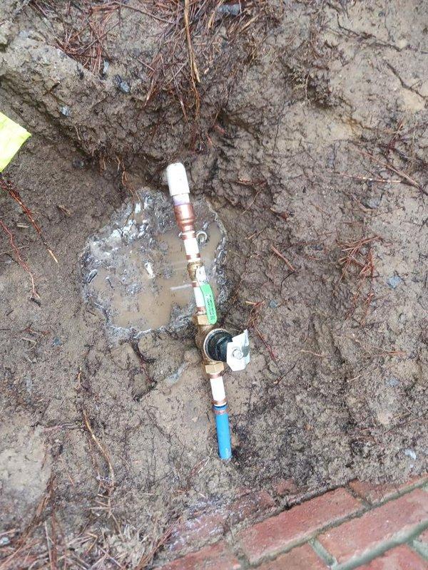 Performed inspection and documentation of backflow prevention assembly and associated pressure monitoring equipment. The backflow preventer, consisting of brass valves with copper and PVC piping connections, was examined at grade level in an excavated area. Verified proper installation of pressure relief valve and assessed condition of all fittings and connections. Documented pressure gauge readings mounted on exterior wall, which indicated system pressure within normal operating parameters. All components were found to be properly installed and functioning as designed for cross-connection control and water supply protection.
