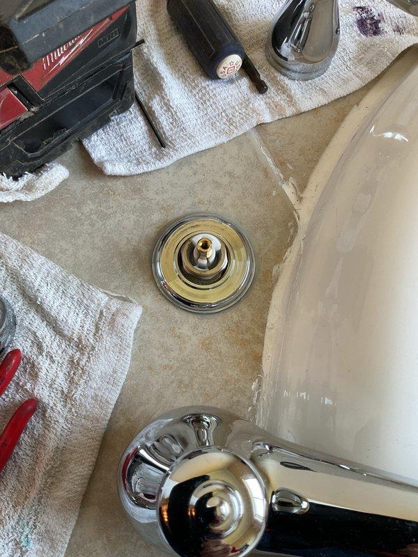 Completed plumbing repair work on bathroom fixtures including bathtub faucet valve assembly replacement and sink drain service. Addressed water flow issues by accessing and replacing the brass valve cartridge behind the tub faucet escutcheon plate, and cleared mineral deposits and buildup from the bathroom sink basin and chrome drain assembly to restore proper drainage function.