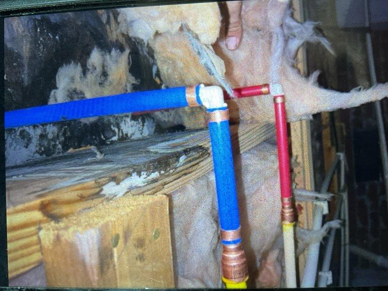 Completed installation of PEX plumbing system in utility room, including hot and cold water supply lines with proper color-coded piping (blue for cold, red for hot). Secured all pipes to structural joists using copper clamps and brackets, ensuring proper support and code compliance. Configured white PVC drain piping with appropriate fittings and connections to washing machine appliance. All plumbing components were properly fastened to wood framing with metal brackets, and connections were completed with standard fittings where PEX lines interface with existing plumbing infrastructure.
