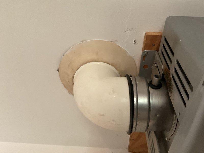 Completed inspection and documentation of HVAC ventilation system components including ceiling-mounted exhaust fan assembly with metal ductwork transition and associated mechanical room piping infrastructure. Verified proper installation of duct connector, ceiling plate mounting, and gas line routing in utility area.