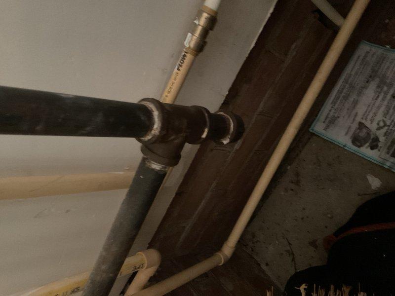 Completed inspection and documentation of HVAC ventilation system components including ceiling-mounted exhaust fan assembly with metal ductwork transition and associated mechanical room piping infrastructure. Verified proper installation of duct connector, ceiling plate mounting, and gas line routing in utility area.