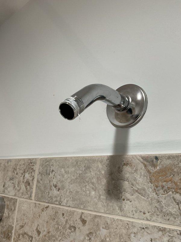Installed new shower fixtures including a chrome wall-mounted showerhead and handheld shower unit with sliding bar in bathroom. Replaced existing shower arm and ensured proper mounting and secure connections for all components