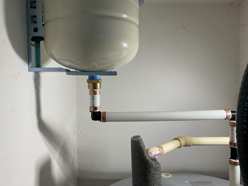 Plumber installed expansion tank to wall using metal bracket to help extend water heaters life by relieving excess pressure when the water inside heats up.